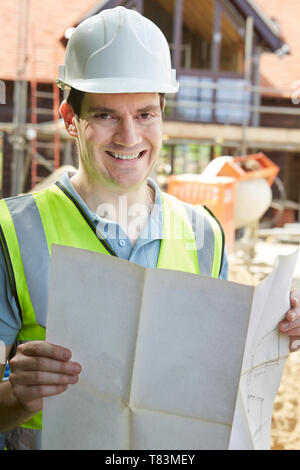 Portrait Of Construction Worker On Building Site Looking At House Plans Stock Photo