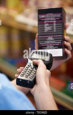 Sales Assistant Checking Stock Levels In Supmarket Using Hand Held Device Stock Photo