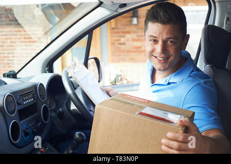 Portrait Of Courier In Van Delivering Package To  House Stock Photo