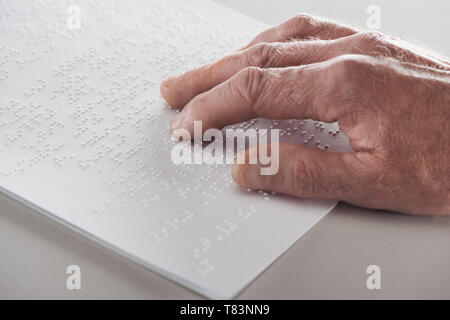close up view of senior man reading braille text isolated on grey Stock Photo