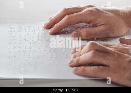 cropped view of man reading braille text with hands isolated on grey Stock Photo