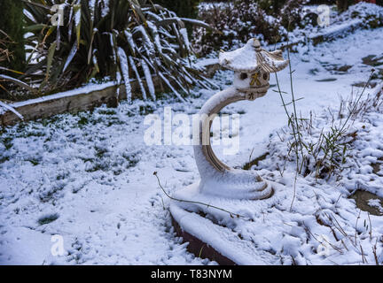 Traditional Japanese stone lantern in garden half covered with snow. Stock Photo