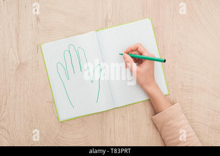 cropped view of female hand on opened notebook near drawn human palm Stock Photo
