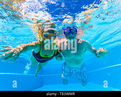 People have fun and enjoy swim underwater in the swimming pool with blue clear water around - summer holiday vacation resort hotel concept for tourist Stock Photo