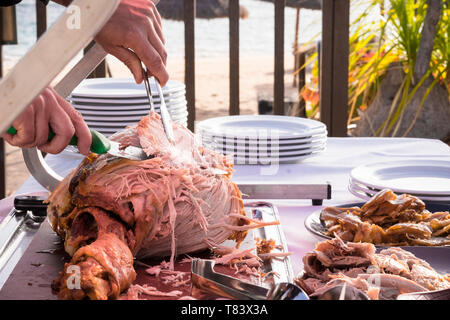 Outdoor celebration with restaurant or catering concept and chef man cutting and serving a tasty nice big turkey - beach in background Stock Photo