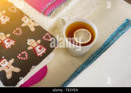 Christmas background - winter clothes with traditional patterns, hot tea with lemon. Stock Photo