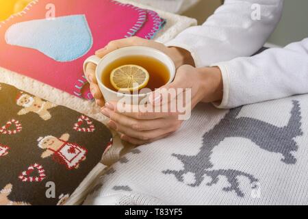 Christmas background - winter clothes with traditional patterns, hot tea with lemon. Stock Photo