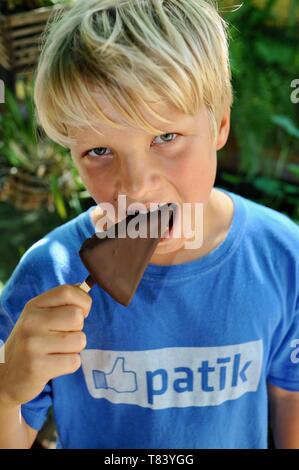 Cute young, boy with blonde hair, blue eyes, age 10-12 and wearing Estonian Facebook t-shirt, eating a frozen dessert treat, Key West, Florida, USA Stock Photo