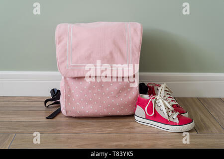 School backpack and sneakers on the floor in a home interior. Stock Photo