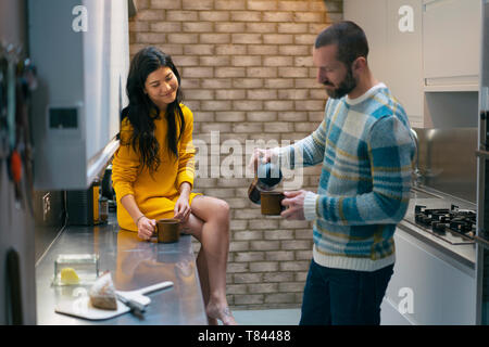 Hipster couple having coffee and talking in kitchen Stock Photo