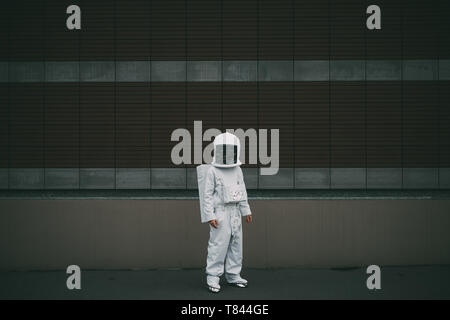 Astronaut standing against striped concrete wall Stock Photo