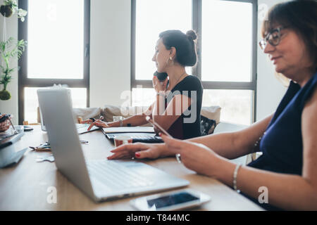 Businesswomen using smartphone and working in loft office Stock Photo
