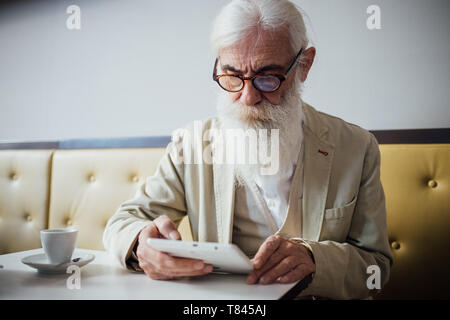 Senior businessman using digital tablet in cafe Stock Photo