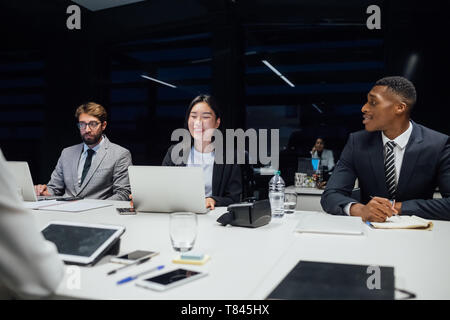 Businesswomen and men laughing during conference table meeting Stock Photo