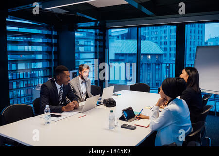 Businessmen and women having discussion over conference table meeting Stock Photo