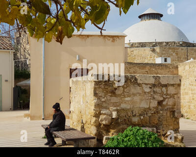 Nicosia, Cyprus - 19 January, 2019: A woman is resting on a bench outside the Omerye Hamam in the old town of Nicosia, Cyprus Stock Photo