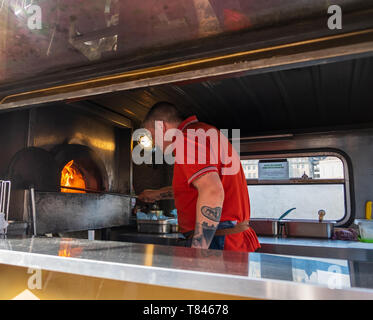 Newcastle, United Kingdom - February 23, 2019: A man bakes pizzas in a rennovated classic van used as a portable canteen serving pizza at Gateshead, N Stock Photo