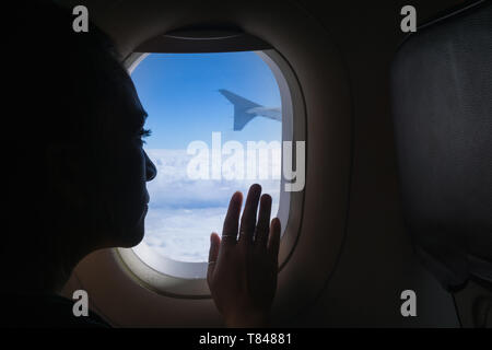 Woman travelling in airplane, looking out window Stock Photo