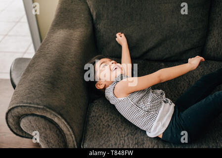 Girl lying on armchair laughing Stock Photo