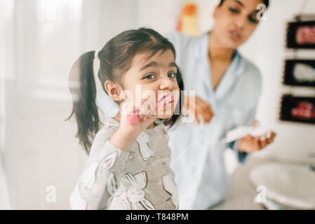 Girl with mother brushing her teeth in bathroom Stock Photo