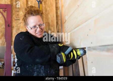 Mature female carpenter using power drill in workshop Stock Photo
