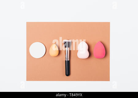 Set of accessories for applying makeup foundation cream, top view. Different cosmetic sponges and flat brush on white table, flat lay. Stock Photo