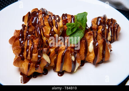 Eclairs with cream and chocolate on a white plate. Stock Photo