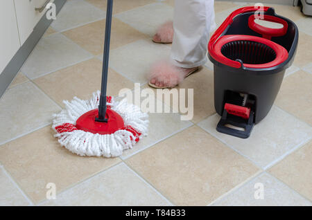 Mop, bucket and woman's feet in elegant slippers on a floor during a housework Stock Photo