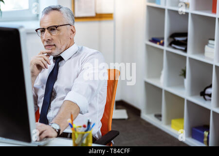 Concentrated senior man with grey beard wearing white shirt Stock Photo