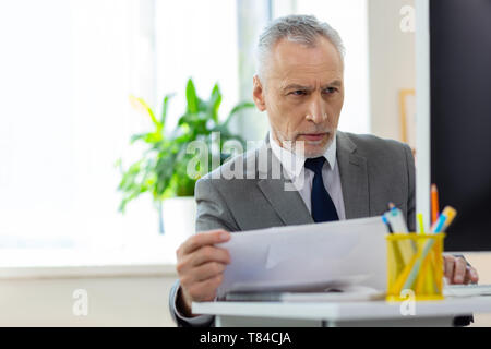 Concerned short-haired old office worker being confused with information on the screen Stock Photo