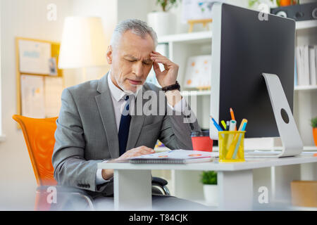 Tired old man being busy office worker and having headache Stock Photo