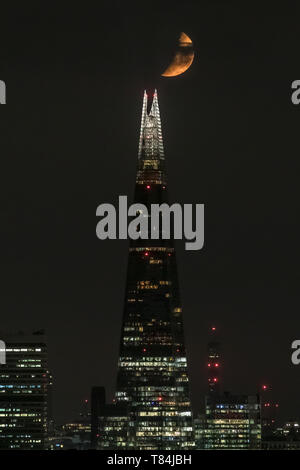 London, UK. 11th May, 2019. UK Weather: A Waxing Crescent moon appears briefly through heavy cloud over The Shard skyscraper building as it continues to set in the early hours of Saturday following a north westerly direction. Credit: Guy Corbishley/Alamy Live News Stock Photo
