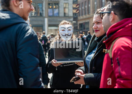 Amsterdam, Netherlands. 111th May 2019. A female activist seen holding a laptop while wearing a Guy Fawkes mask during the demonstration. Hundreds of activists gathered at the Dam square in the center of Amsterdam to participate in The Cube of Truth. Anonymous for the Voiceless hosted a 24-hour Cube of Truth in Dam Square, Amsterdam. The Cube of Truth is a peaceful static demonstration similar to an art performance. This demonstration operates in a structured manner that triggers curiosity and interest from the public; the activists attempt to lead bystanders to a vegan conclusion through a co Stock Photo
