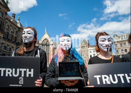 Amsterdam, Netherlands. 111th May 2019. A female activist seen holding a laptop while wearing a Guy Fawkes mask during the demonstration. Hundreds of activists gathered at the Dam square in the center of Amsterdam to participate in The Cube of Truth. Anonymous for the Voiceless hosted a 24-hour Cube of Truth in Dam Square, Amsterdam. The Cube of Truth is a peaceful static demonstration similar to an art performance. This demonstration operates in a structured manner that triggers curiosity and interest from the public; the activists attempt to lead bystanders to a vegan conclusion through a co Stock Photo