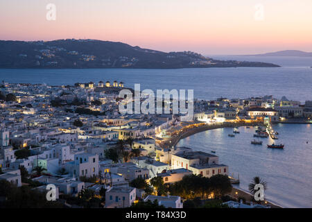 Mykonos Town, Mykonos, South Aegean, Greece. View over the illuminated town and harbour from hillside, dusk. Stock Photo