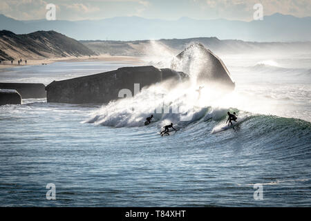 Capbreton (south-western France): surfers on waves, beach “plage de la Savane”, with blockhouses in the background Stock Photo