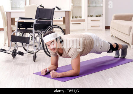 Injured young man doing exercises at home Stock Photo