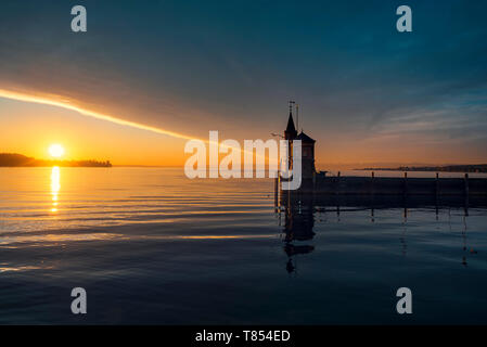 Early summer morning on lake Bodensee, Konstanz, Germany. Sunrise over water and lighthouse. Cloudscape and sun reflected on the water. Stock Photo