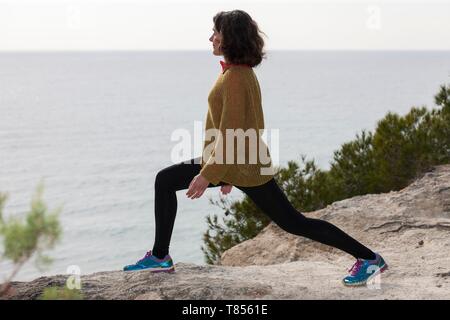 Woman stretching next to the sea Stock Photo