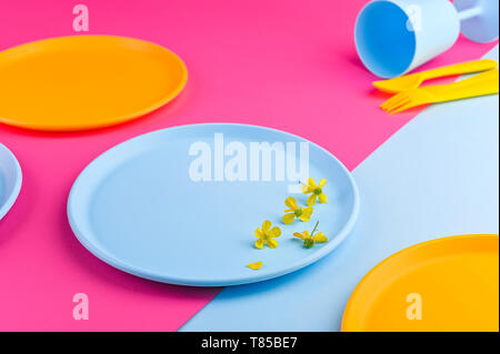 Multi-colored plastic picnic utensils on a pink background. Glasses and dinner plates. Eco dishes. Flat lay. Copy space Stock Photo