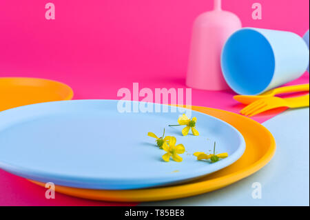 Multi-colored plastic picnic utensils on a pink background. Glasses and dinner plates. Eco dishes. Flat lay. Copy space Stock Photo