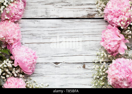 Pink Peonies and Baby's Breath flowers over a white rustic wood table background  with copy space for your text. Flat lay. Stock Photo