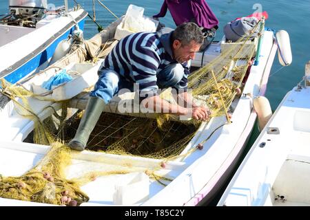 Albanian fisherman on a small fishing boat repairing fishing net Saranda Albania Stock Photo