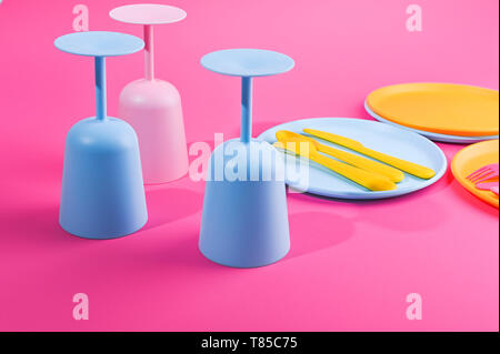 Blue plastic glasses and plates. Color dishes for a summer picnic. Top view. Pink and yellow color on the photo. Copy space Stock Photo