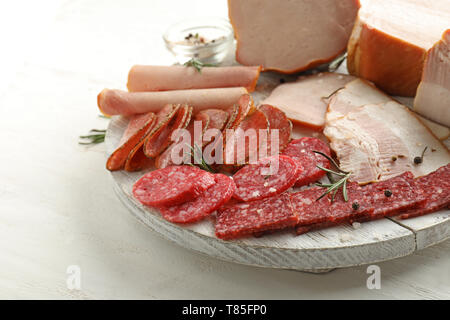 Assortment of delicious deli meats on wooden board Stock Photo