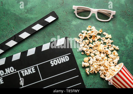 Composition with tasty popcorn and clapperboard on green background Stock Photo