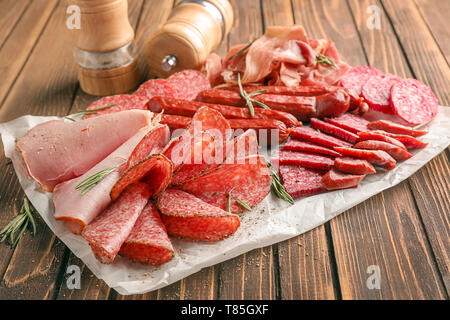 Variety of delicious deli meats on wooden table Stock Photo