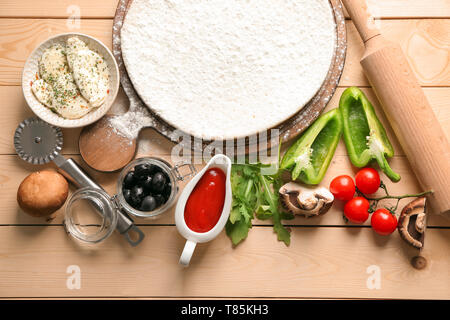 Raw dough with ingredients for pizza on wooden table Stock Photo