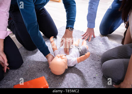 Specialist Giving Baby CPR Dummy First Aid Training To His Colleagues Stock Photo