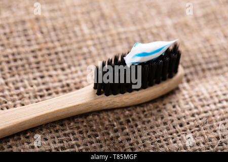 Close-up Of Black Bamboo Toothbrush With Toothpaste On Sack Cloth Stock Photo